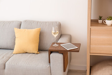 Glass of wine with tablet computer on armrest table in room