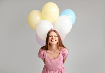 Fototapeta na wymiar Young woman with balloons on grey background