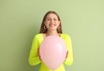 Young woman with balloon on color background