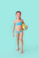 Little girl in swimsuit and with paddles on color background