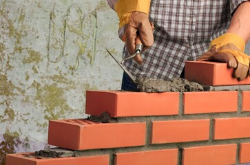 Man worker installing brick masonry wall with a trowel