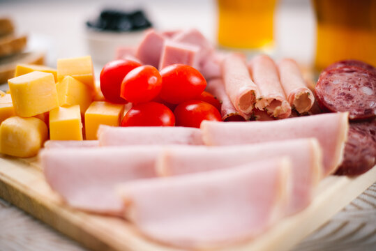 Selecci&oacute;n de fiambres en tabla de madera de lomo ahumado, lomo cocido, jam&oacute;n cocido, queso, salame de mil&aacute;n, acompa&ntilde;ado de aceitunas y cerveza