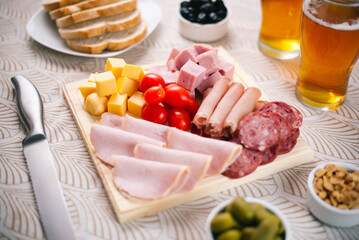 Selección de fiambres en tabla de madera de lomo ahumado, lomo cocido, jamón cocido, queso, salame de milán, acompañado de aceitunas y cerveza