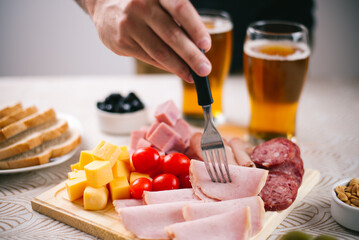 Selección de fiambres en tabla de madera de lomo ahumado, lomo cocido, jamón cocido, queso, salame de milán, acompañado de aceitunas y cerveza