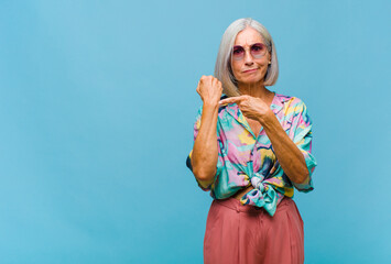 middle age cool woman looking impatient and angry, pointing at watch, asking for punctuality, wants...
