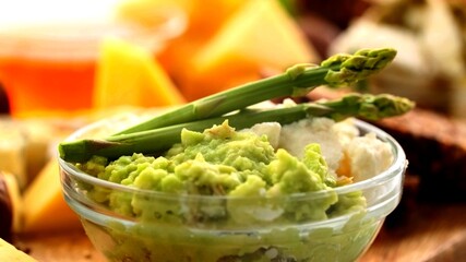 A close up on two asparagus on a bowl of Guacamole