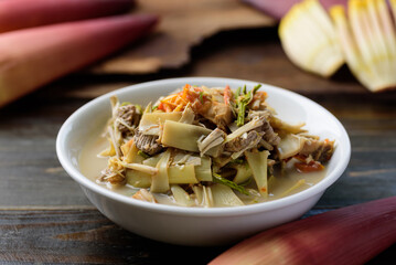 Northern Thai food (Kaeng Hua Plee), banana flower spicy soup with pork in a bowl on wooden table, Local Thai food