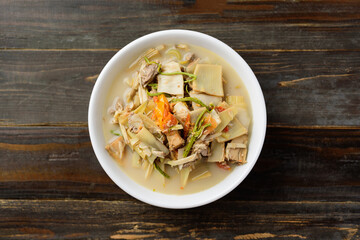 Northern Thai food (Kaeng Hua Plee), banana flower spicy soup with pork in a bowl on wooden table, Local Thai food
