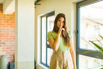 young pretty woman looking serious and cross with finger pressed to lips demanding silence or...