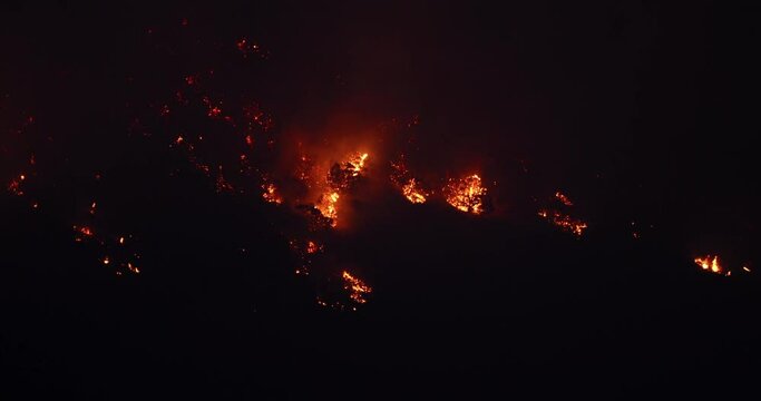 Forest fire dark night high wilderness mountain Utah. Intense man caused wild and forest fire destroyed a mountain side and valley. Fire fighting crew on ground supported by aircraft and helicopters.