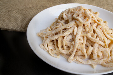 Raw homemade pasta on white plate