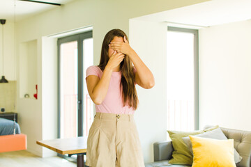 young pretty woman covering face with both hands saying no to the camera! refusing pictures or...