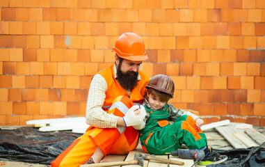 Family business. Man and boy in protective helmets at a construction site. New home for the family.