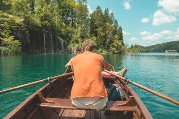 Rear view of man paddling rowboat at plitvice lakes national park, rowboat travel in beautiful Croatia waterfalls