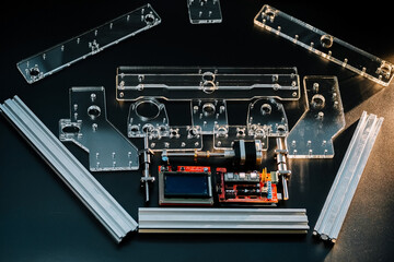 a set of parts for a laser machine on a black background, silver backlight, flat lay arduino board for controlling the machine and v slot aluminum profile lies .