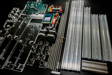 a set of parts for a laser machine on a black background, silver backlight, flat lay arduino board for controlling the machine and v slot aluminum profile lies .