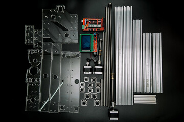 Fototapeta premium a set of parts for a laser machine on a black background, silver backlight, flat lay arduino board for controlling the machine and v slot aluminum profile lies .