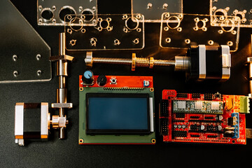 a set of different parts for a laser machine on a black background, orange illumination, flat lay. arduino board for controlling the machine and v slot aluminum profile lies .