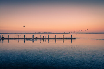 Fototapeta na wymiar Fishing docks at sunset and birds flying around. Dreamy image.