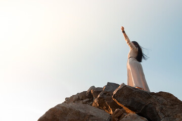 Beautiful brunette girl in a dress meditates at sunset in the mountains, climb the mountains.