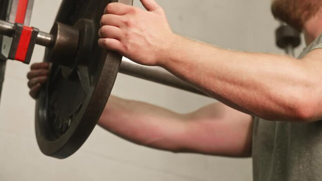 Man's hands sliding 45 pound weight plate off of barbell, Medium Shot, Low Angle, Slow Motion