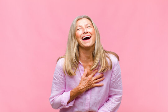middle age pretty woman laughing out loud at some hilarious joke, feeling happy and cheerful, having fun