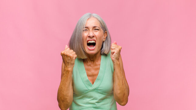 middle age pretty woman shouting aggressively with annoyed, frustrated, angry look and tight fists, feeling furious