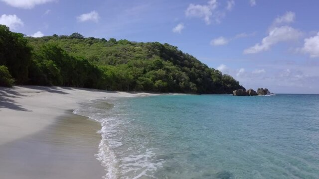 Low drone shot along shoreline of Anse le Roche Beach, Carriacou, Grenada