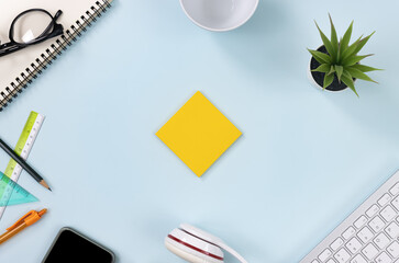 Yellow Stick Note or Note Pad and Office Supplies as Keyboard,Pen,Pencil,Office Plants,Notebook,Glasses,Smartphone,Headphone,Coffee Cup on Modern Clean Creative Office Desk or Table on Top View