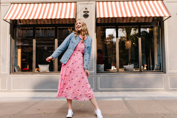 full length photo of smiling young girl dancing at the street at front of cafe