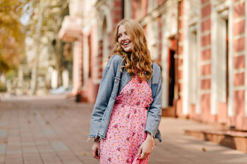 cheerful happy blonde girl smiling and looking to the left on the background of a building