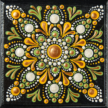 Mandala dot art painting on wood tiles. Beautiful mandala hand painted by colorful dots on black wood. National patterns with acrylic paints, handwork, dot painting. Abstract dotted background.