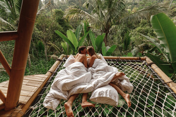 A hidden place. Sleeping couple wake up in the morning with nature view, couple lie in hammock, hug...