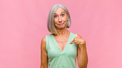 middle age pretty woman covering face with hand and putting other hand up front to stop camera,...