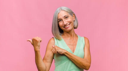 middle age pretty woman feeling happy, satisfied and powerful, flexing fit and muscular biceps, looking strong after the gym