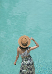Girl posing near the pool in a fashionable swimsuit with pool reflect in the background / summer activity