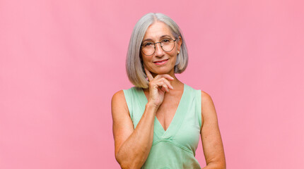 middle age pretty woman laughing shyly and cheerfully, with a friendly and positive but insecure...