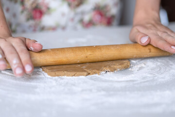 The girl rolls out the dough with a rolling pin.