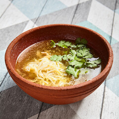 Classic chicken broth in brown pottery bowl