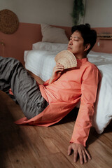 Gay sit on the floor, lean at the bed.