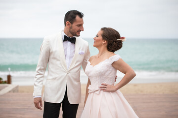 Latino Bride and groom with white tuxedo looking at each other