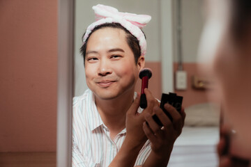 Reflection in a mirror of happy gay while makeup his face.
