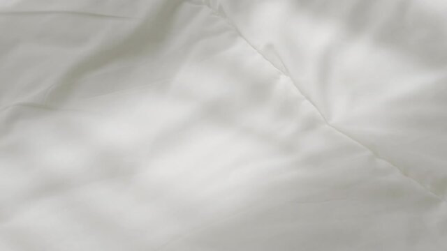 Hand touching very soft on a wrinkled white cloth and swept it down completely.