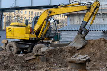 Yellow excavator on wheels digs the ground. Earthwork with an excavator.