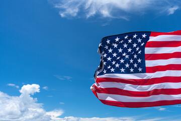 Waving USA flag under blue sky background.