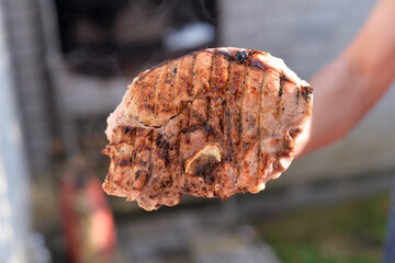 the process of cooking grilled meat with a crust on the grill at home, on an autumn day