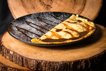 Banana crepe served on a plate withy iceing suger