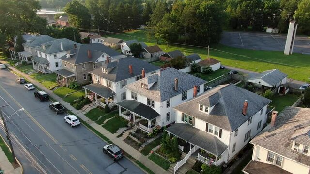 Establishing shot of large houses in United States, homes line small town street in America, USA housing residential community neighborhood during summer, aerial drone view