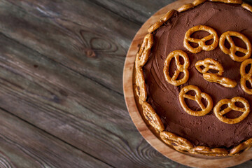 Chocolate beer cake decorated with mini bretzels on a wooden table copy space.