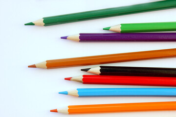 Fototapeta premium Colored pencils on a white background. Lots of different colored pencils. Colored pencil. Pencils are very sharp. Pencils lie on the right and unevenly. Close-up. Copy space. Background. Flat lay